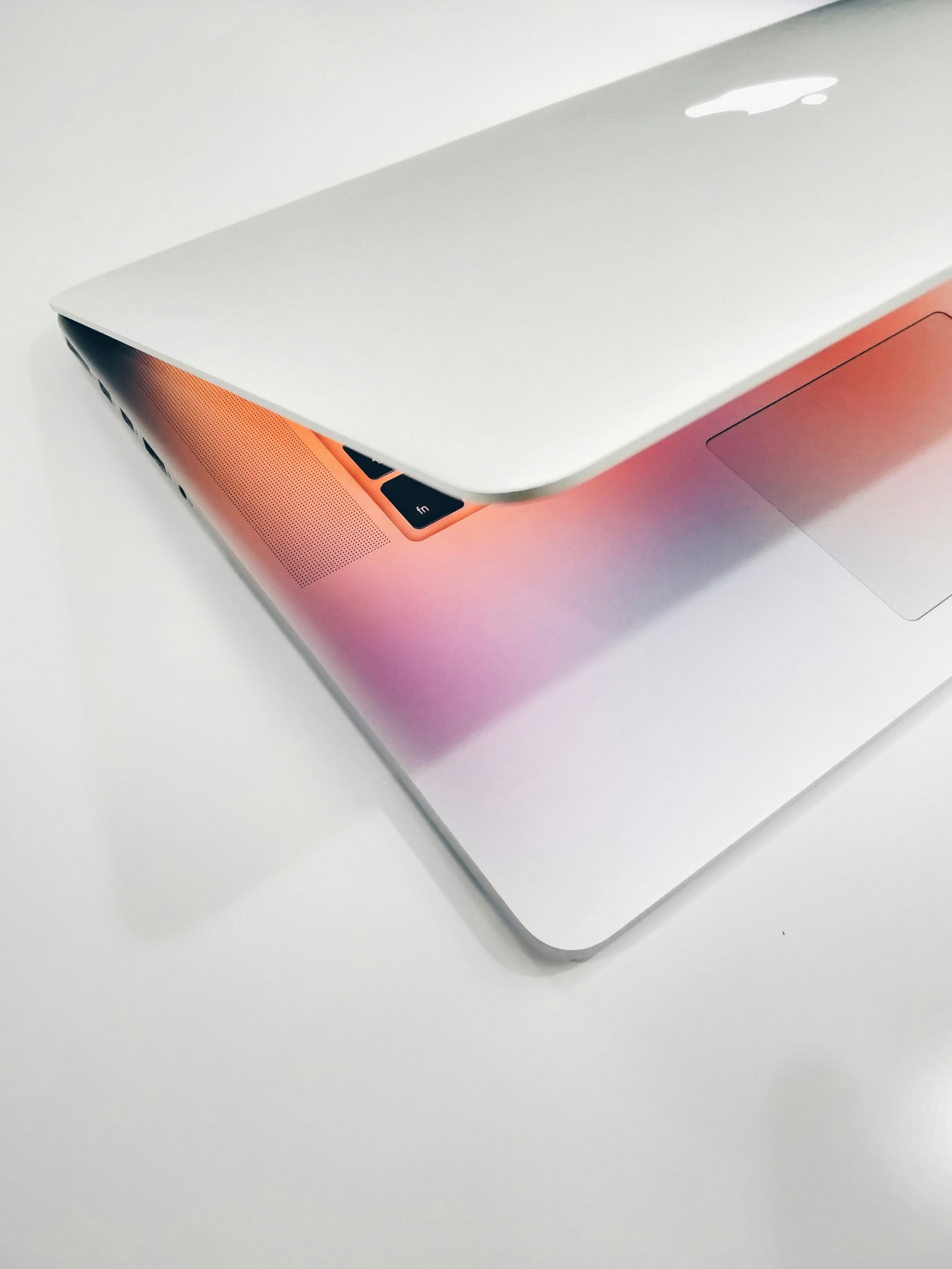 A half-closed laptop with a glowing reflection from the screen.