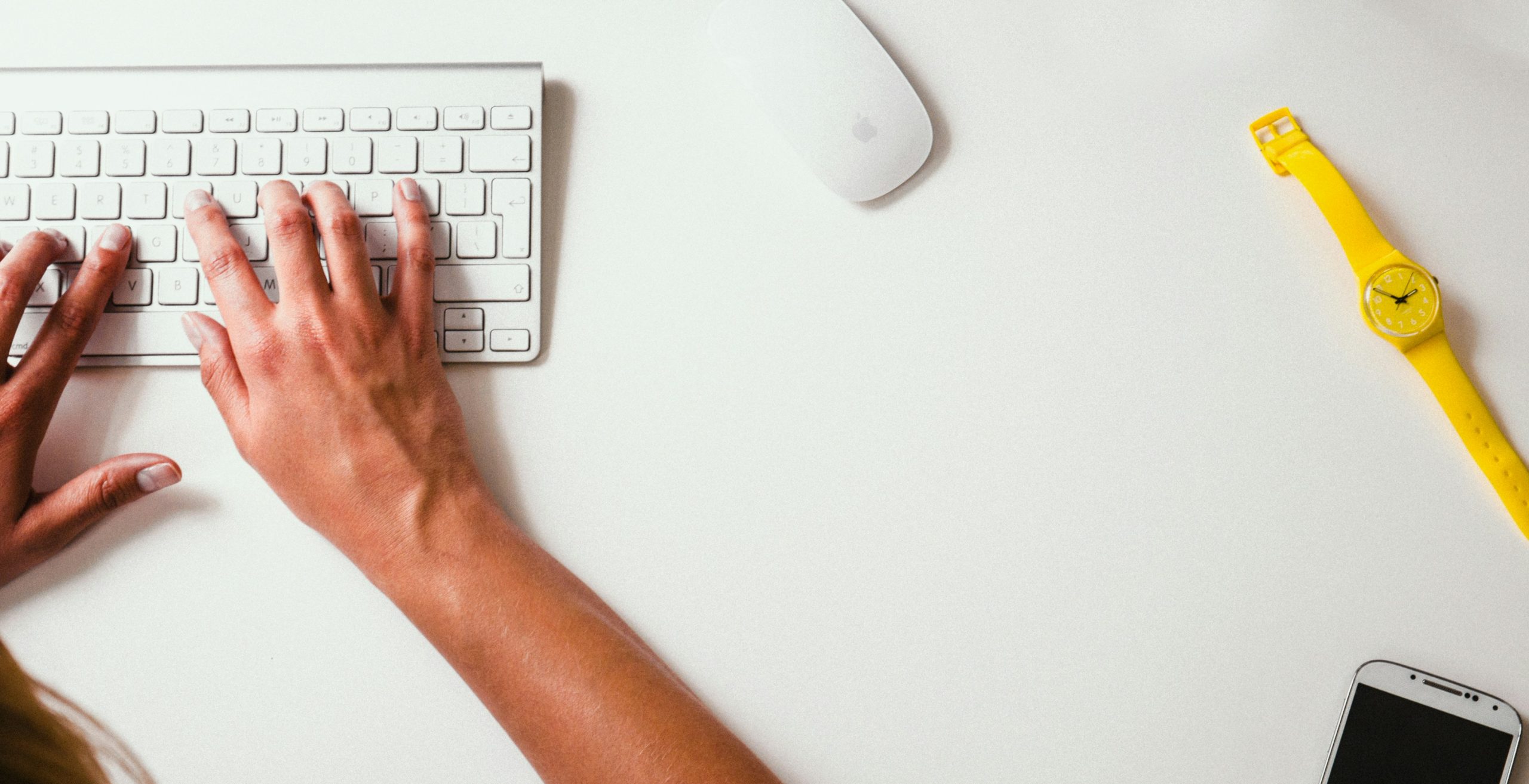 A photograph of someone typing on a keyboard with a mouse. 